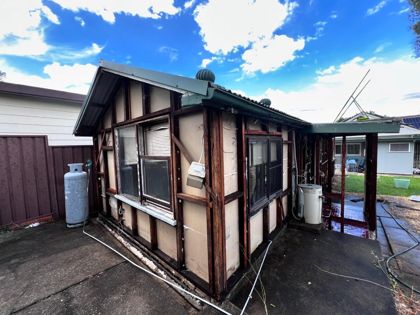 Small, Aged Shed With Wood Trim and Damaged Siding —Ecowave Solutions Asbestos Removal In Gosford, NSW