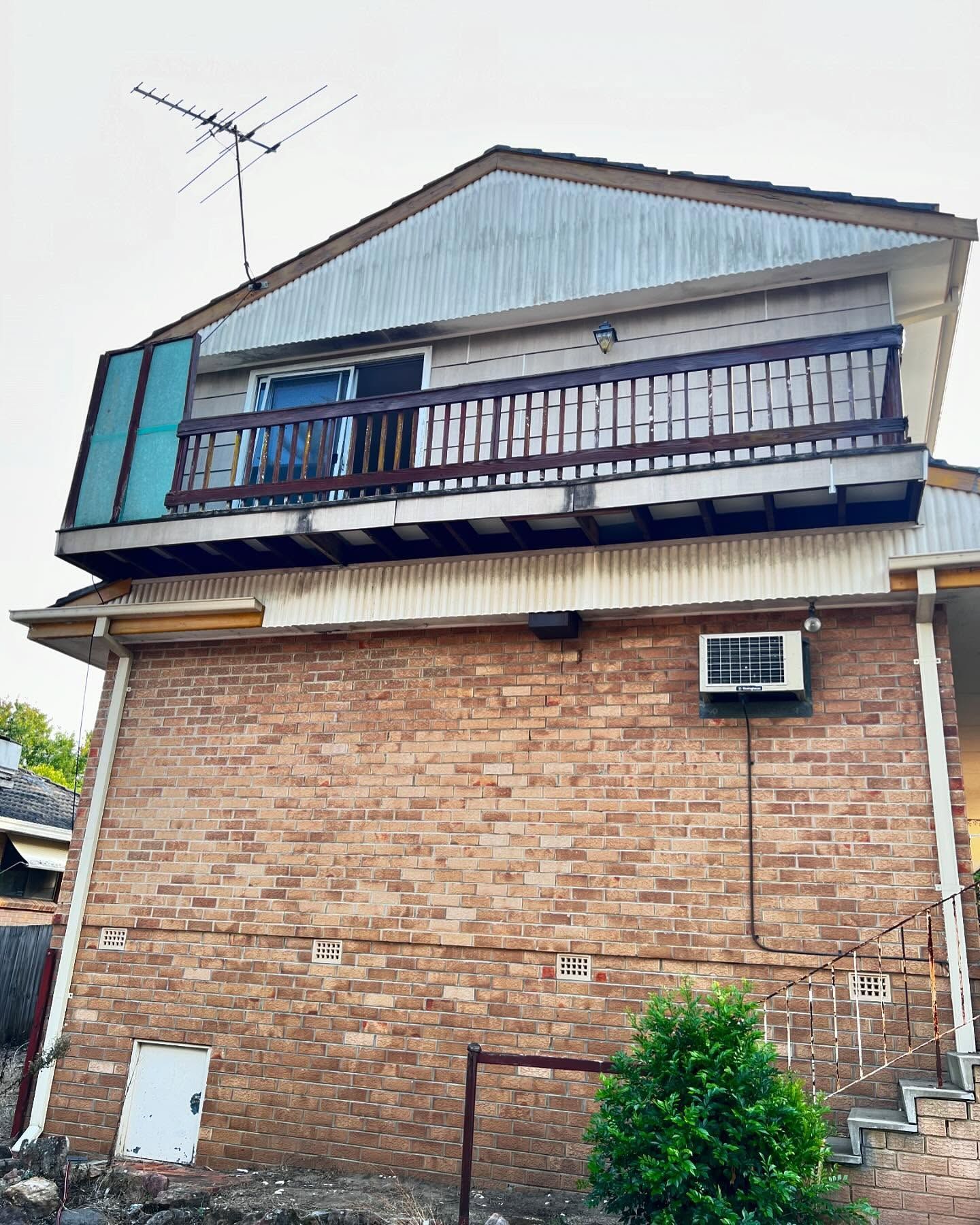 Brick House With a Balcony, Antenna, and Air Conditioning Unit — Ecowave Solutions Asbestos Removal In Gosford, NSW
