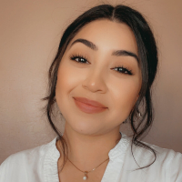 A woman wearing a white shirt and a necklace is smiling for the camera.
