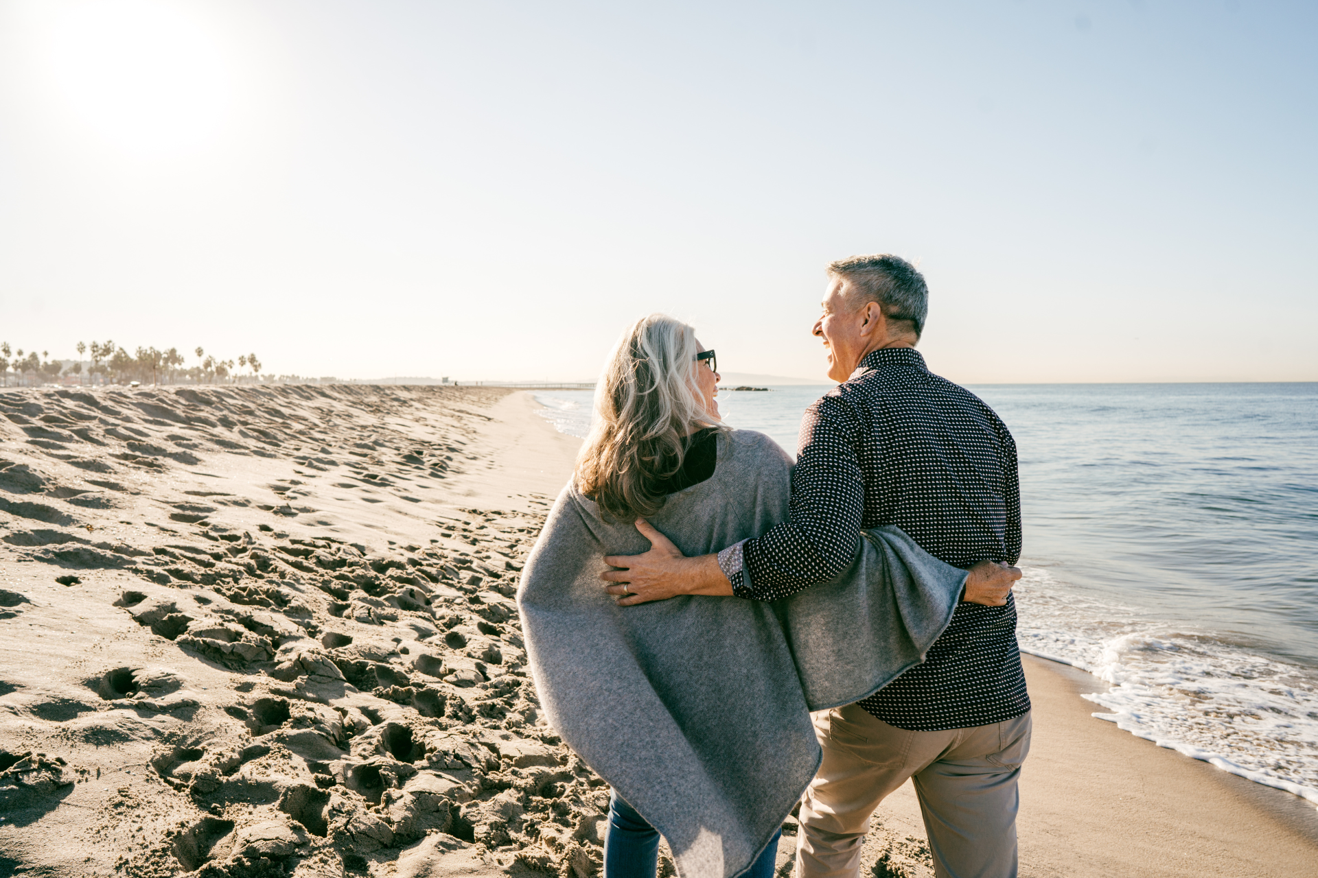 A man and a woman are walking on the beach.