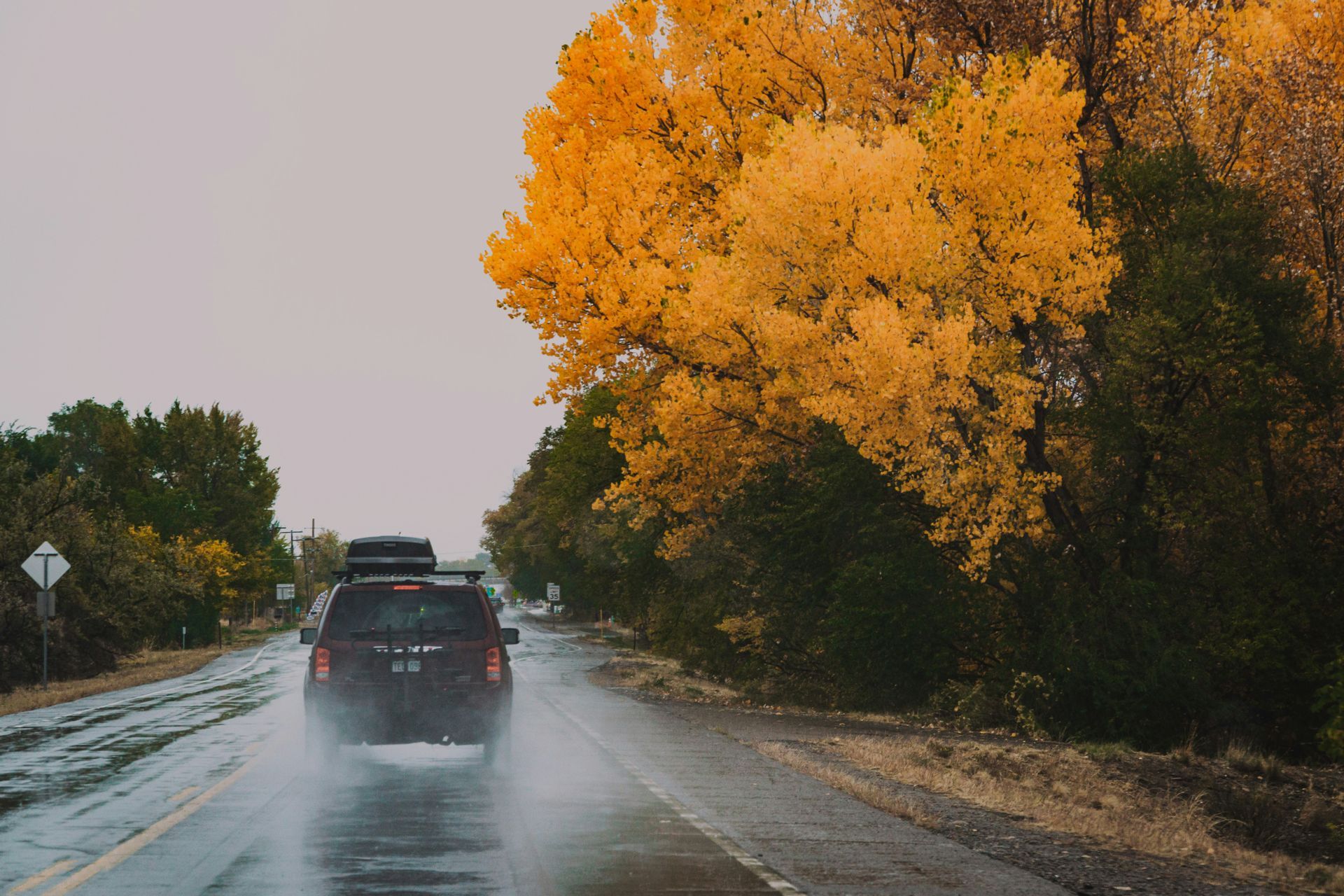 A car is driving down a wet road in the rain.