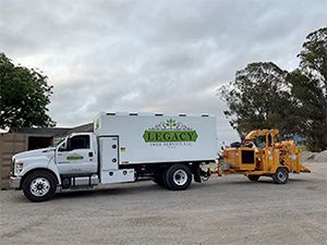 a white truck with the word legacy on the side is parked next to a tree chipper .