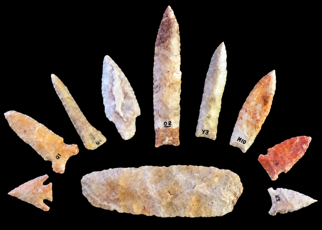 Flat-lay of Native American stone artifacts on aged linen with identification tags