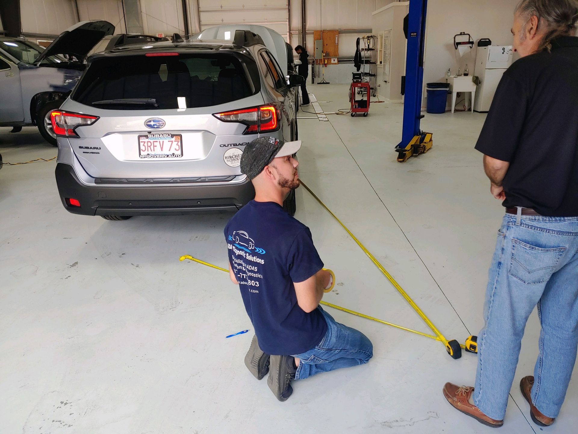 A man measuring a car with a tape measure