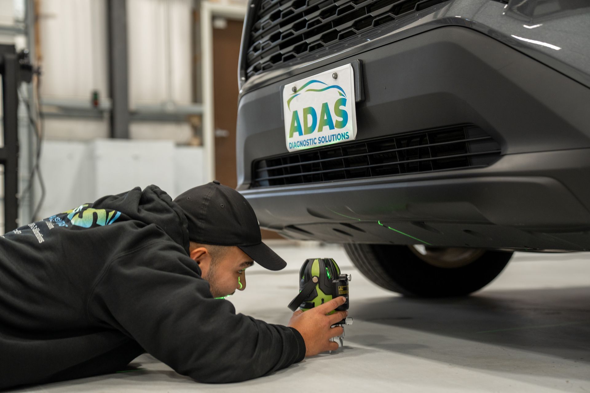 A man is laying on the ground looking underneath a car.