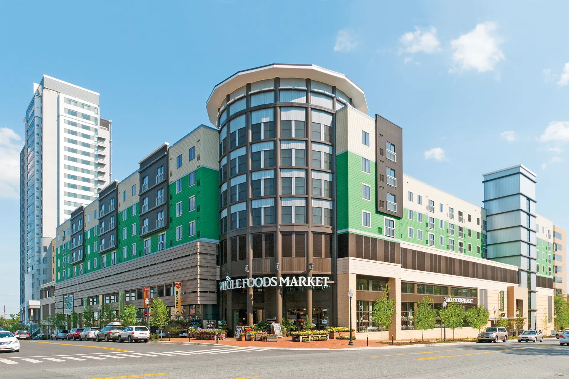 A large building with a lot of windows is sitting on the corner of a street.