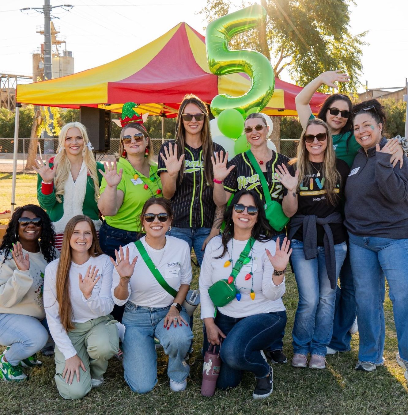 A group of women in green jackets are posing for a picture.