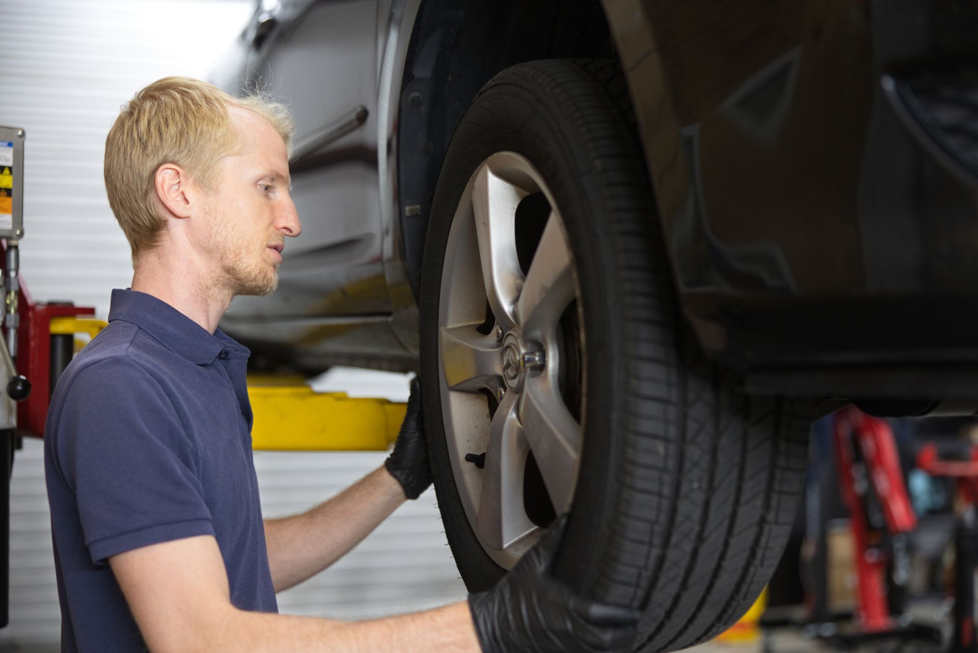 True Tech Automotive technician checking tire tread and condition on a lifted vehicle in Waynesboro VA