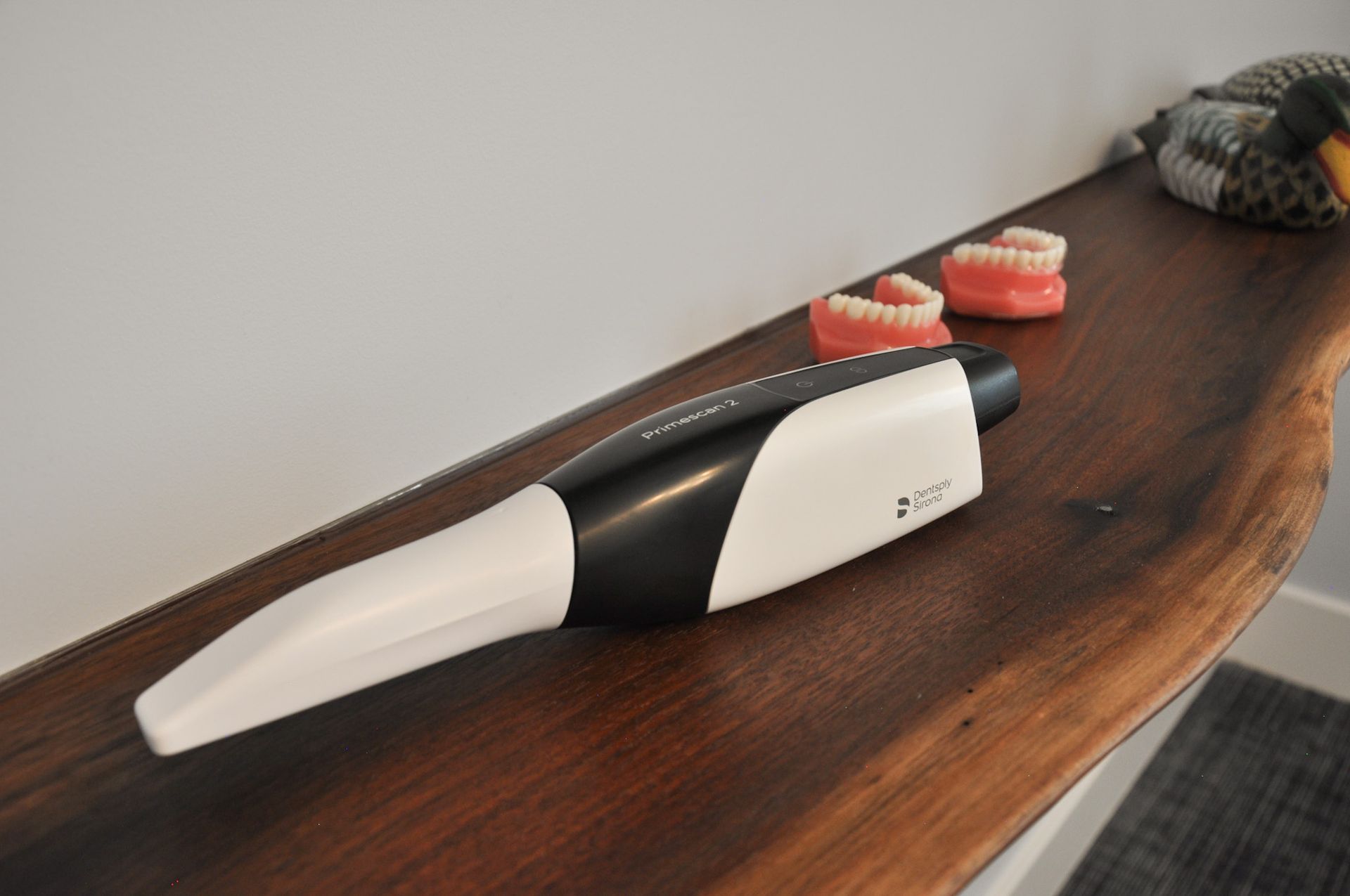 A dental scanner on a wooden table next to model teeth.