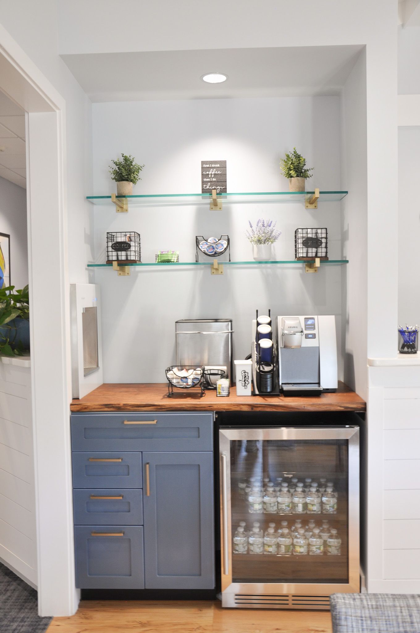 Built-in coffee station with blue cabinets, wood countertop, and shelves. Includes a beverage cooler and various appliances.