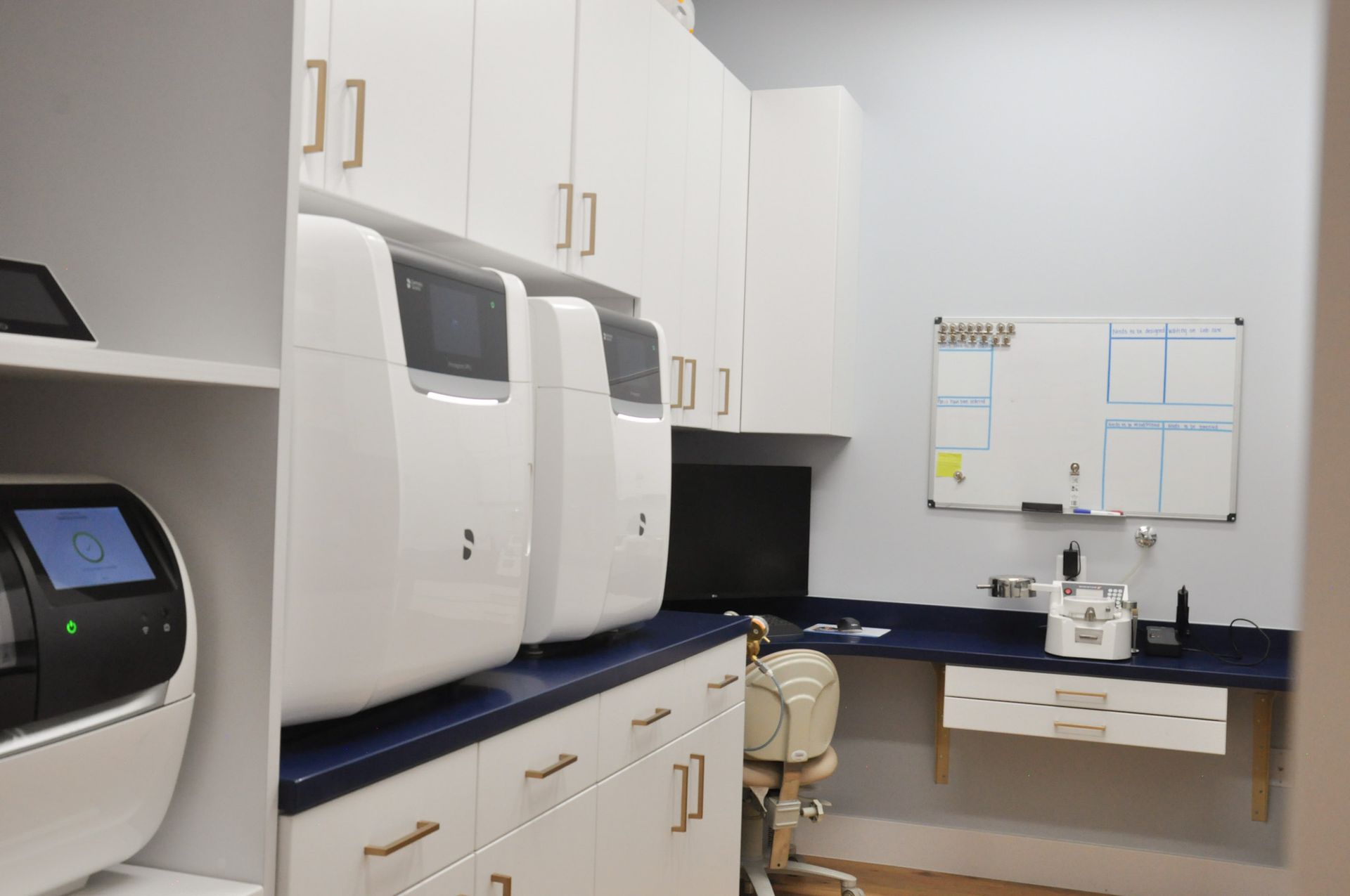 A lab interior with white cabinetry, medical equipment, and a small whiteboard on the wall.
