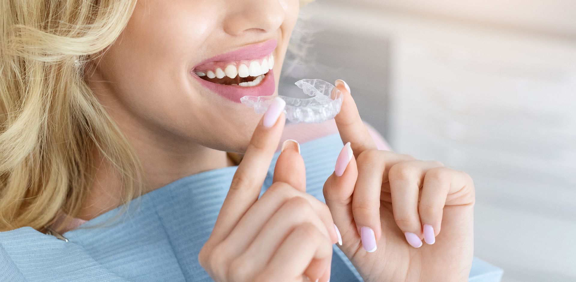 A woman is holding a clear brace in her mouth.