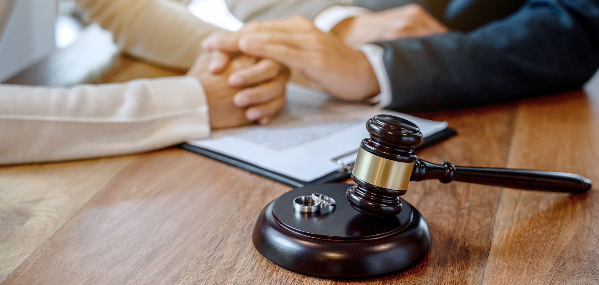 Handshake beside a judge’s gavel on a desk, suggesting a legal agreement.