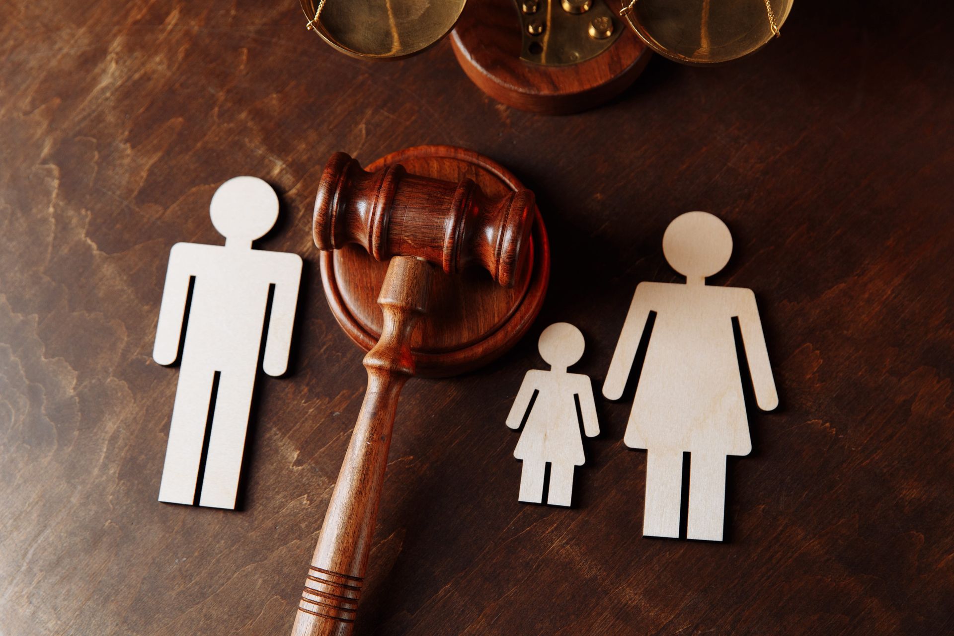 Wooden gavel and family icons on a dark table, suggesting family law or custody decision