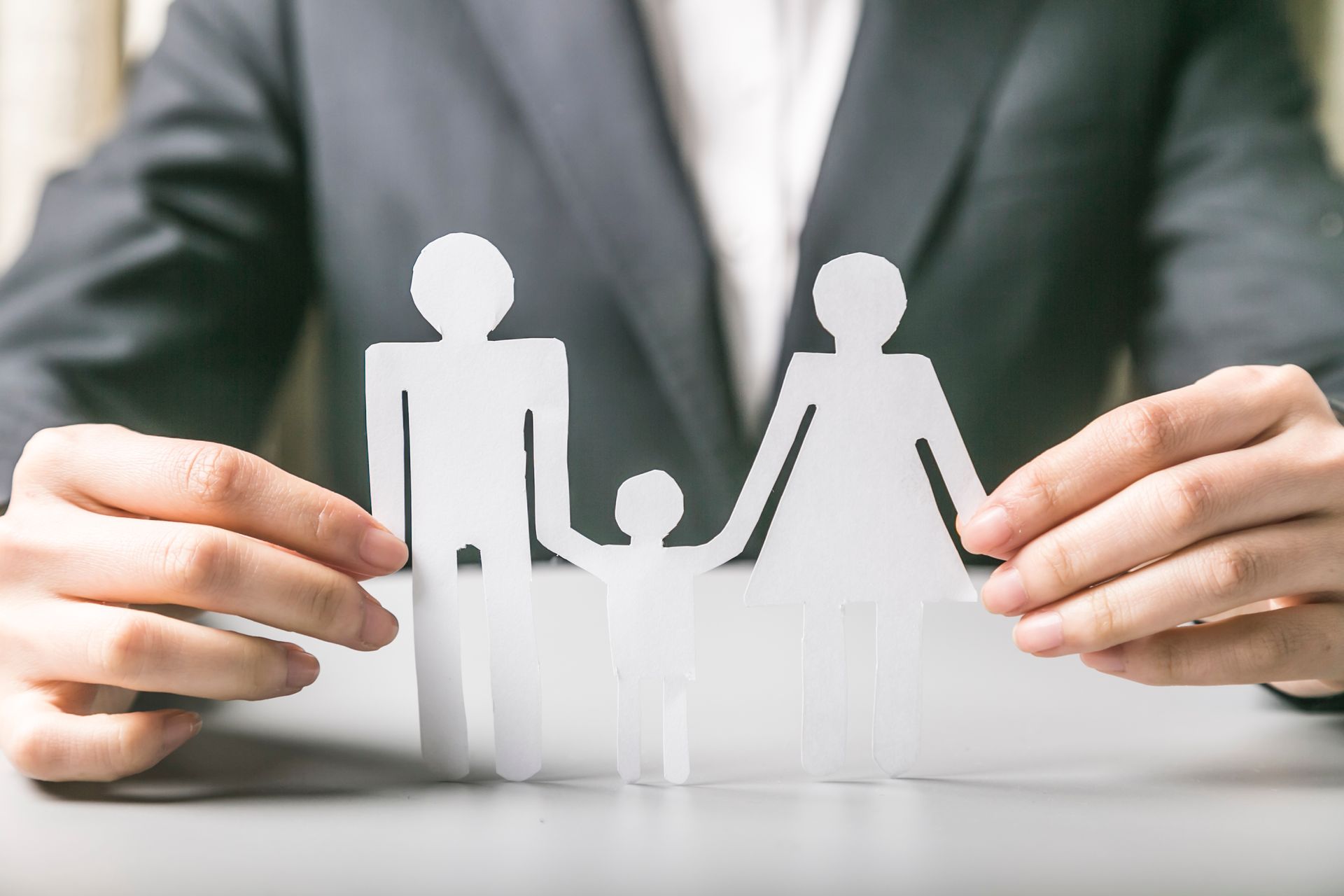 Person in suit holding paper cut-out family.