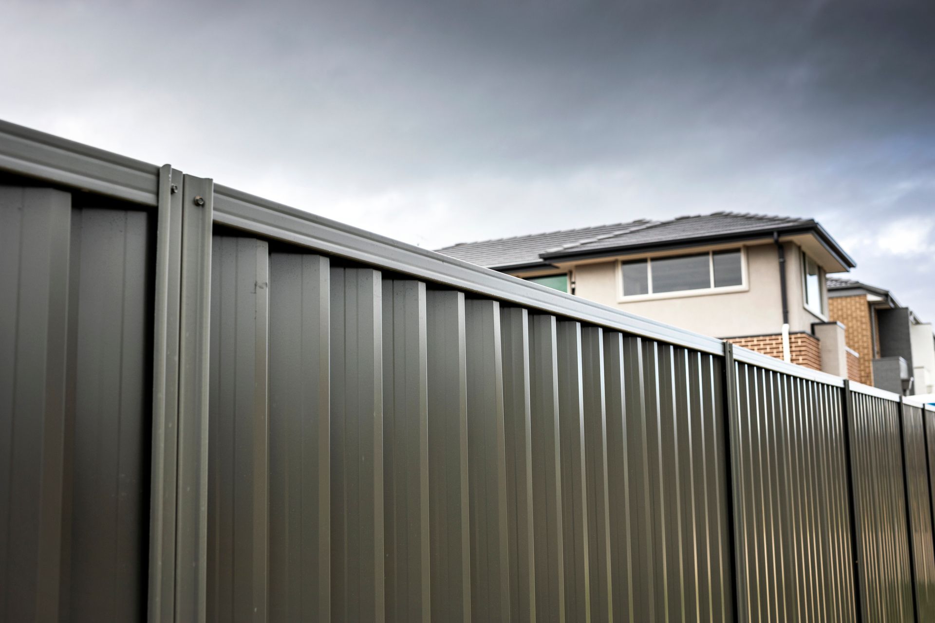 Metal boundary fence, house rooftops in suburb | Gold Coast|