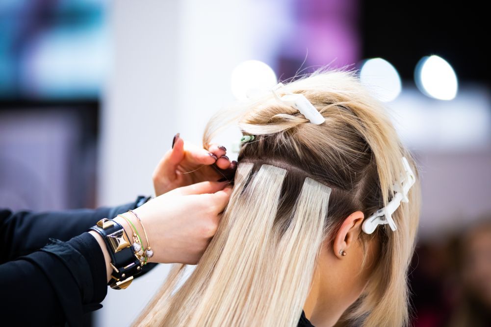 A woman is getting her hair done by a hairdresser in a salon.