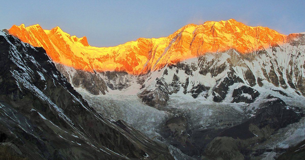 Breathtaking sunrise illuminating the snow-capped peaks of the Annapurna range, seen from Annapurna Base Camp in Nepal.