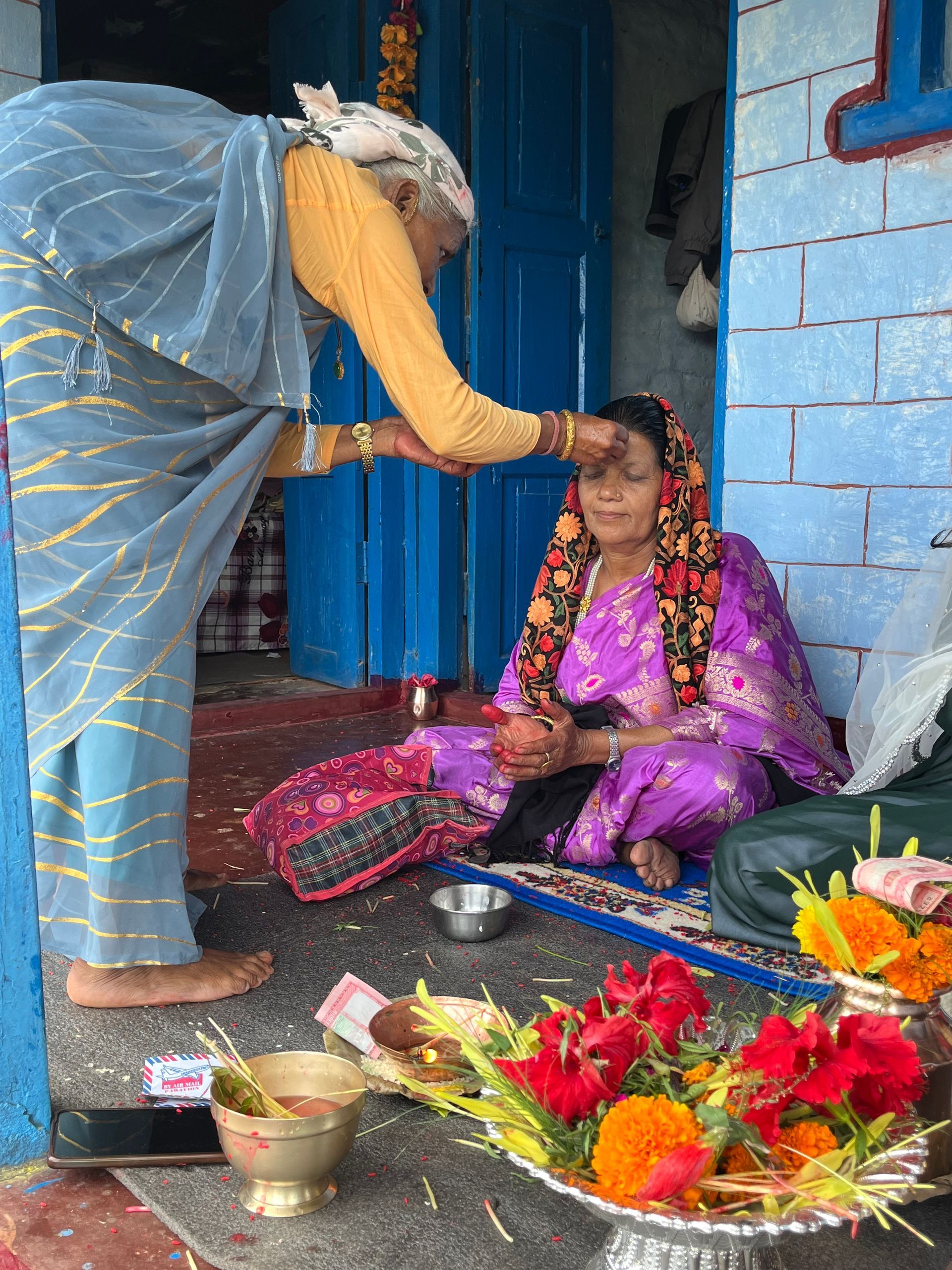 Elderly woman giving Dashain tika and blessings in a Nepali home