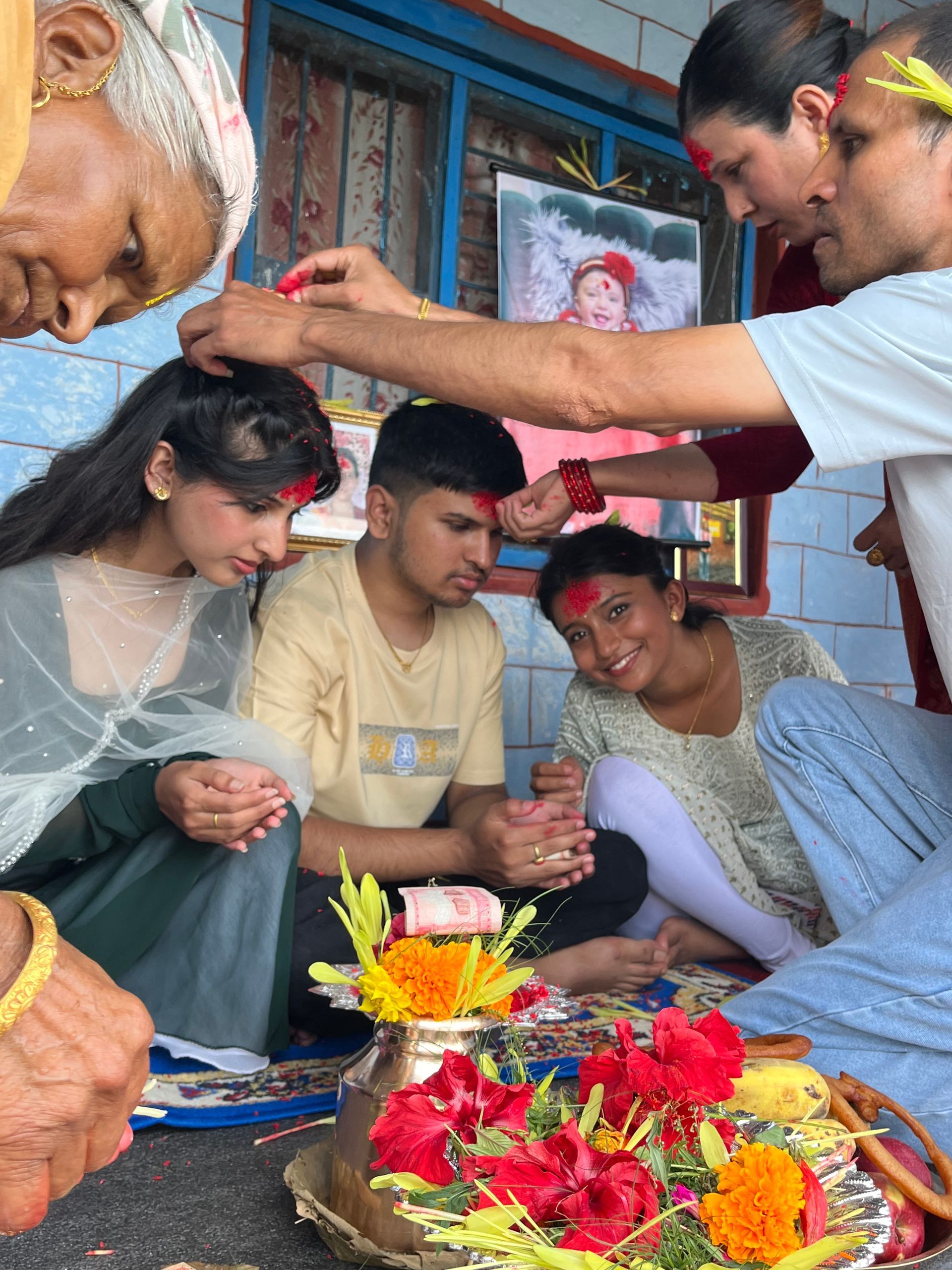 Elders placing Jamara and red Dashain tika on young family members in a Nepali village home