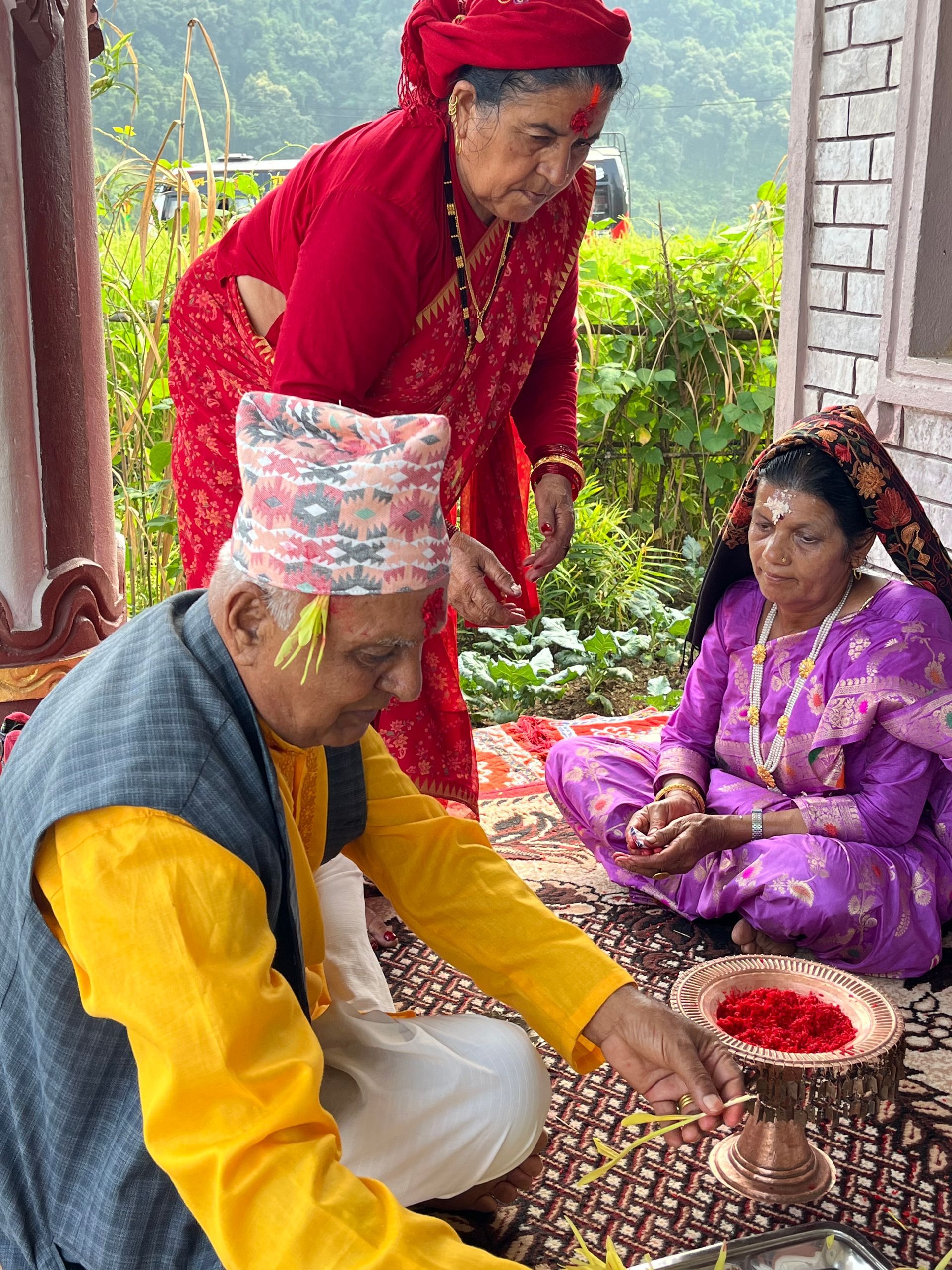 Nepali elder in a dhaka topi preparing tika on Vijaya Dashami