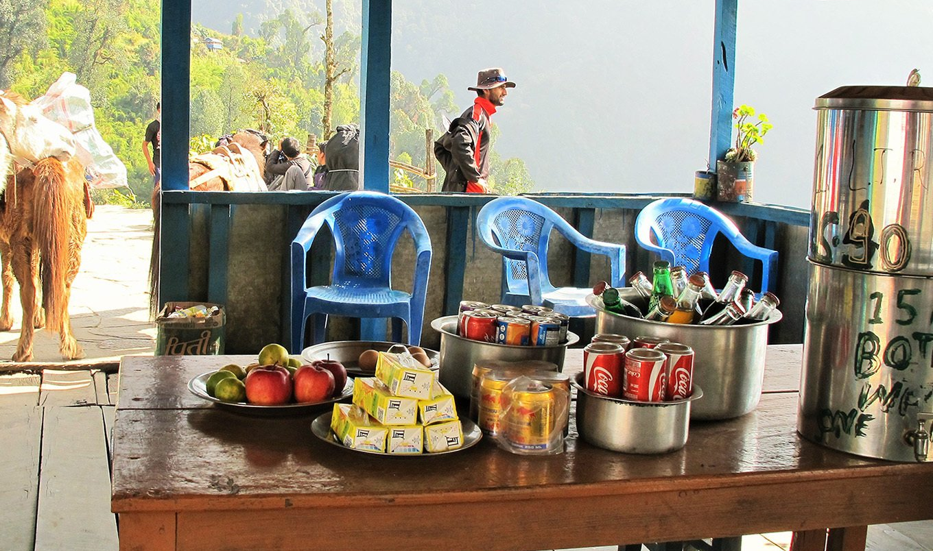 Local teahouse stop on a trekking trail in the Annapurna region with fresh fruit, drinks, and mountain views, Nepal
