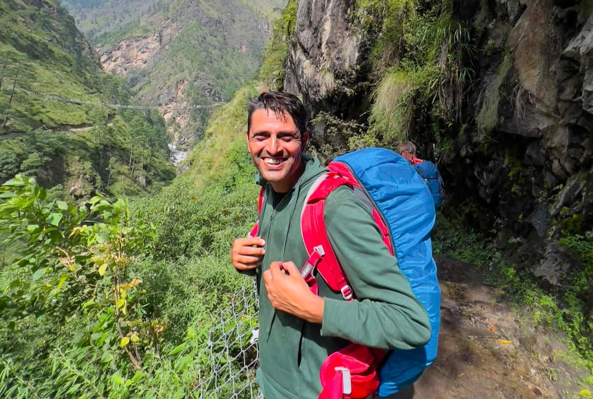 Guest and local trekking guide smiling together on a forest trail in Nepal