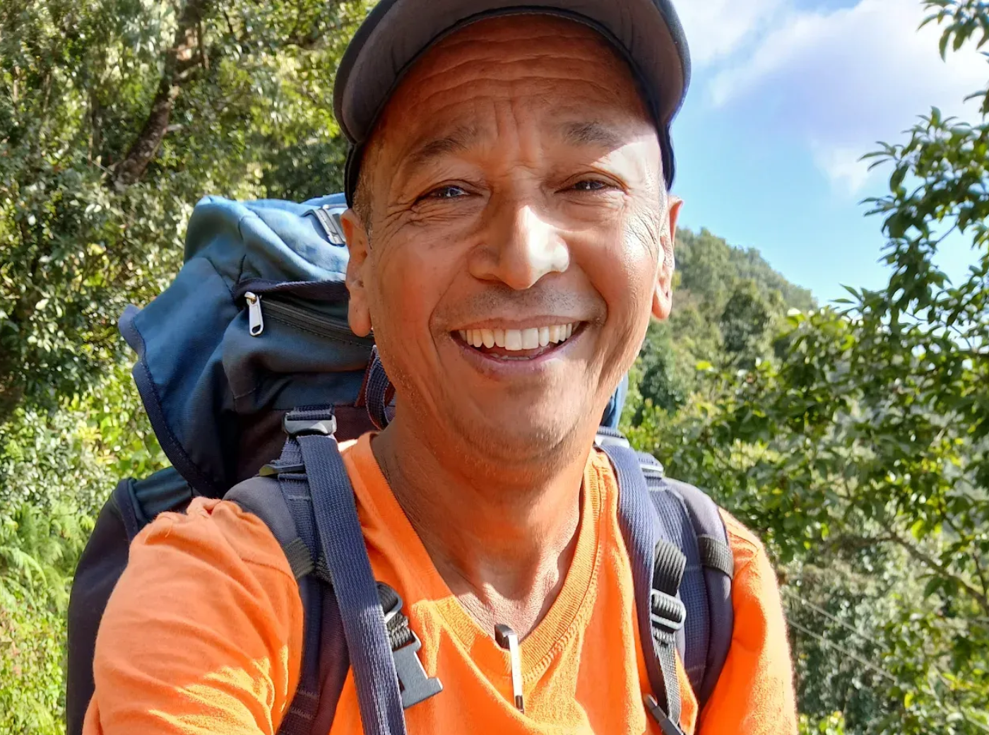 Smiling local trekking guide in orange jacket on a mountain trail in Nepal