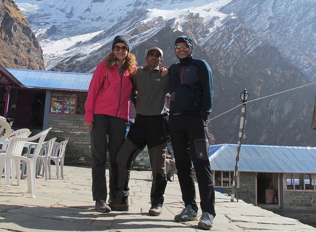 Trekkers posing together with a helper, surrounded by majestic peaks, showcasing the beauty of trekking in Nepal.