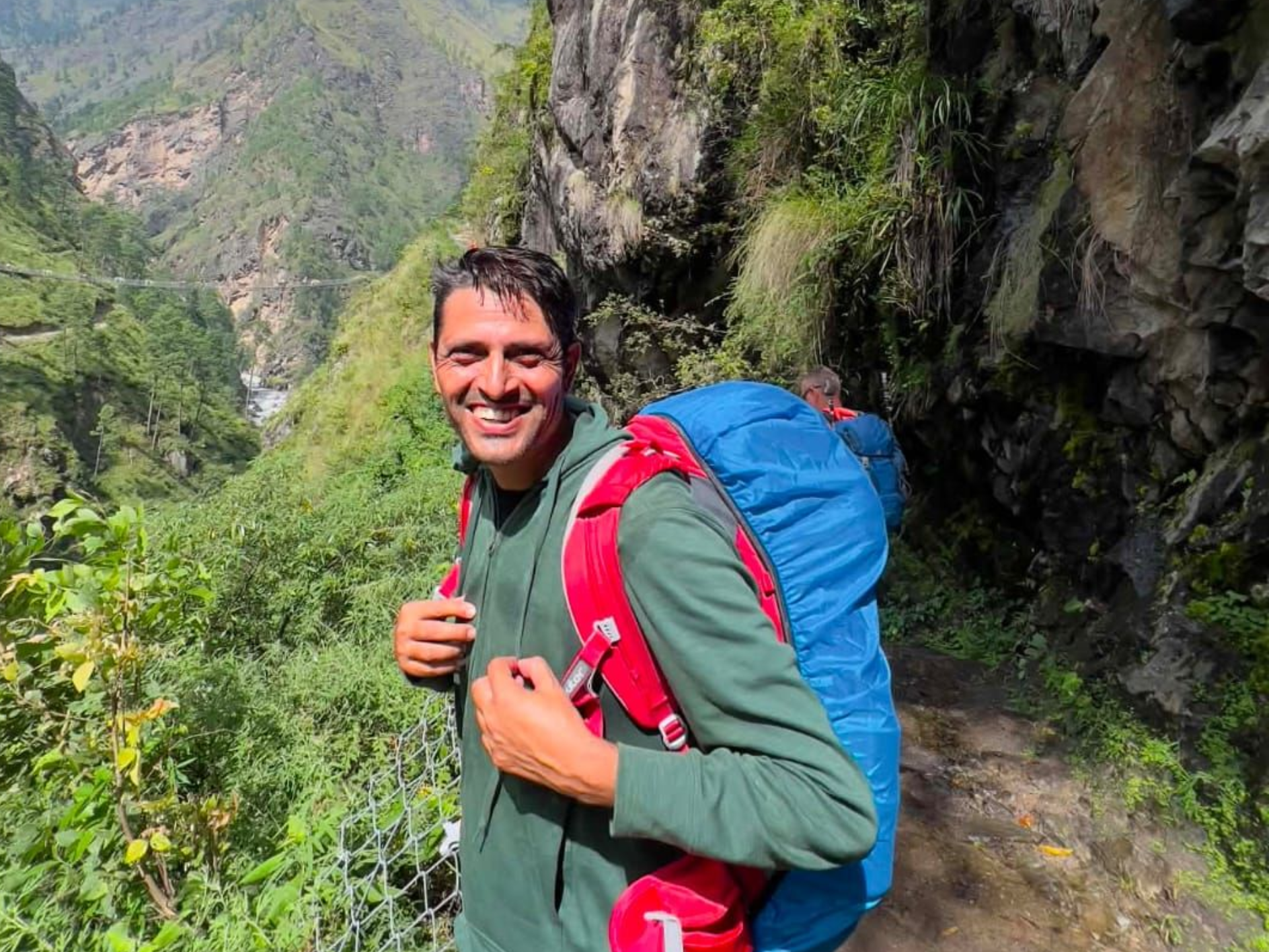 Guest and local trekking guide smiling together on a forest trail in Nepal