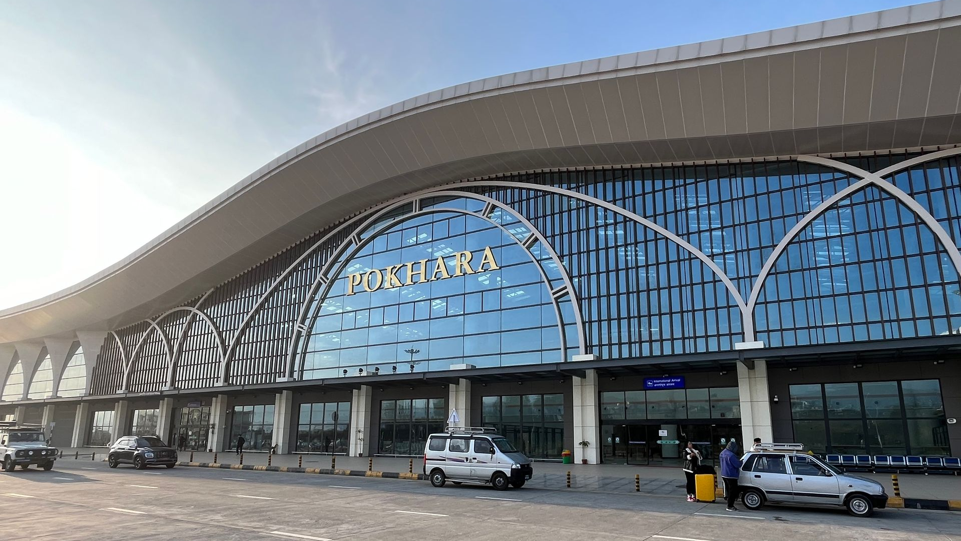 Pokhara International Airport terminal with its curved roof, glass arches and the International Arri