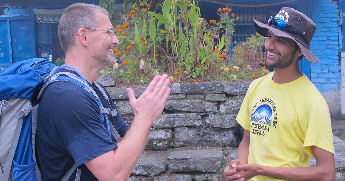 Trekking guide and tourist engaged in a friendly conversation during a trek in Nepal, showcasing local hospitality.