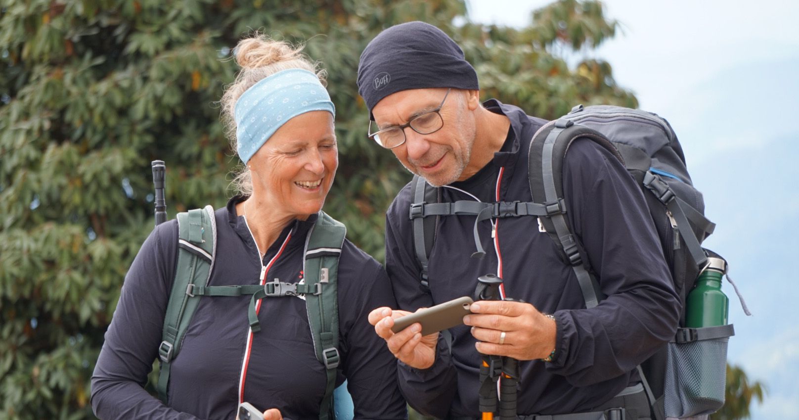 Happy trekkers checking their route on the Annapurna Trek in Nepal, enjoying the scenic surroundings.