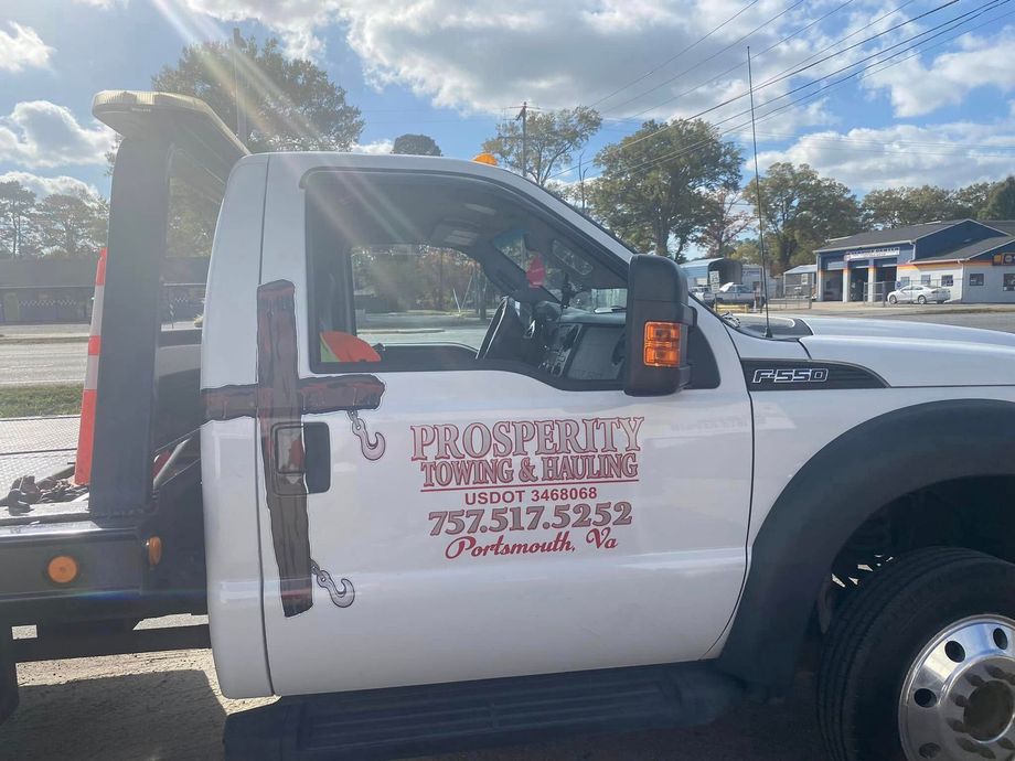 White tow truck with company logo parked outdoors in bright sunlight