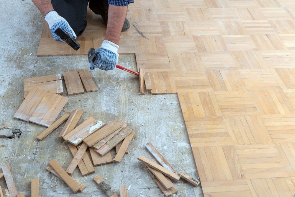 Person Installing Wood Parquet Flooring, Using Tools — Kalora Carpentry & Restorations in Charlestown, NSW