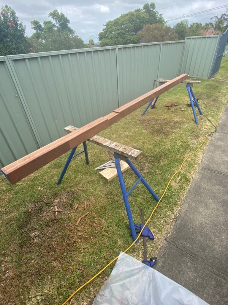 Wooden Beam on Blue Sawhorses Outdoors, Likely for Construction — Kalora Carpentry & Restorations in Charlestown, NSW