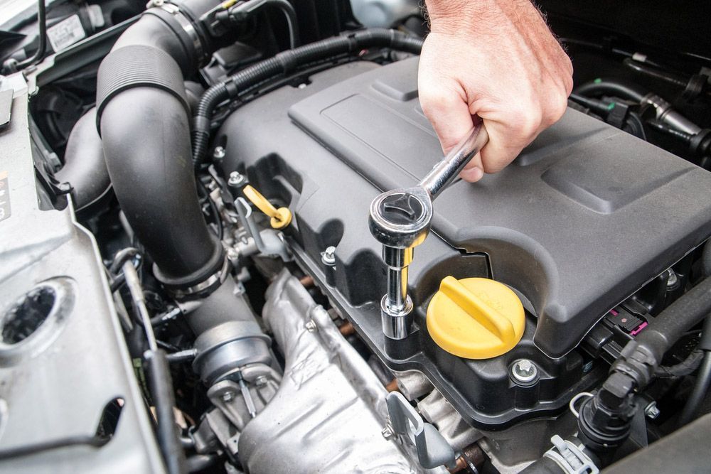 A Person Is Working On A Car Engine With A Wrench — Crossway Wreckers & Mechanical In Gordonvale, QLD