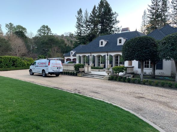 White SUV and pickup parked outside a large stone house with a gravel driveway and manicured lawn
