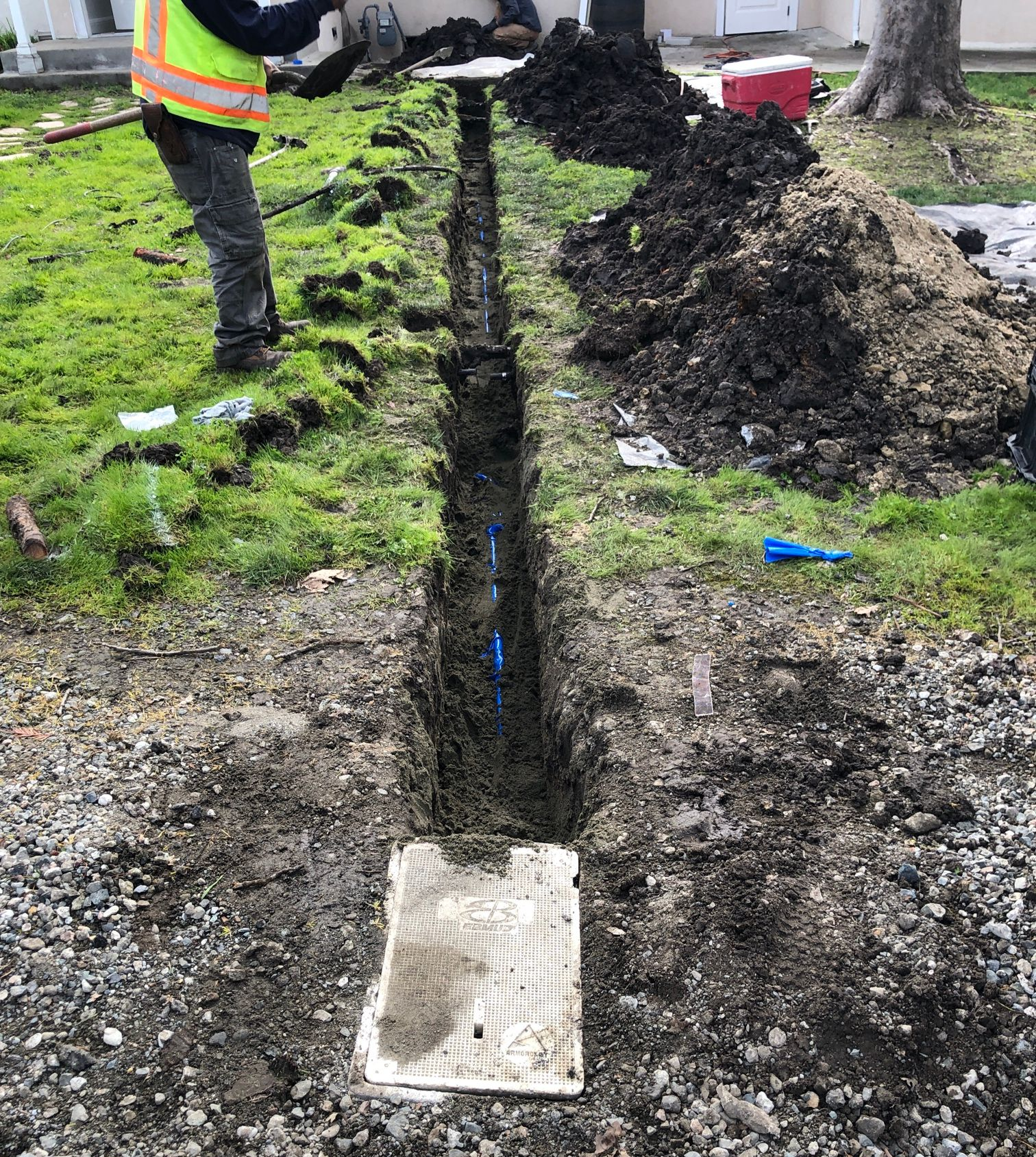 Trenched ground with exposed copper pipes and a blue pipe crossing the dirt.