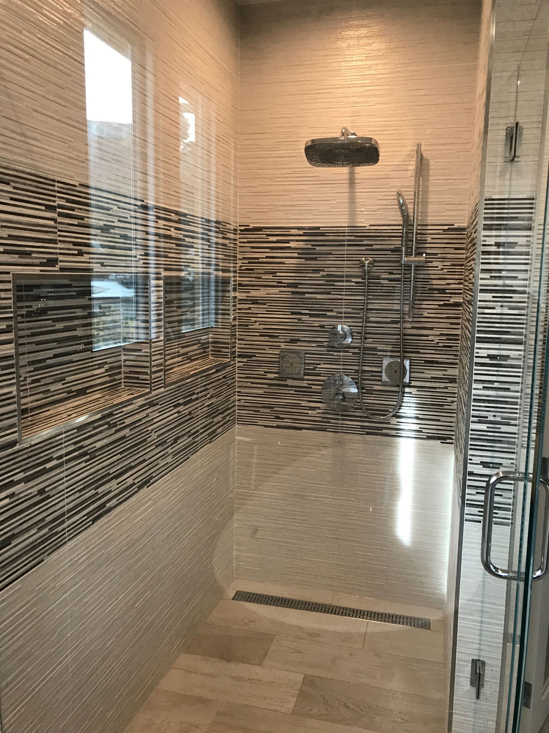 Walk-in shower with mosaic tile walls, glass door, rain showerhead, and bench seat