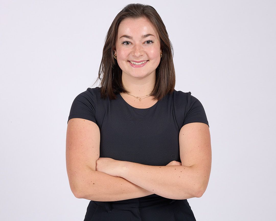 Smiling woman with crossed arms against a light gray background