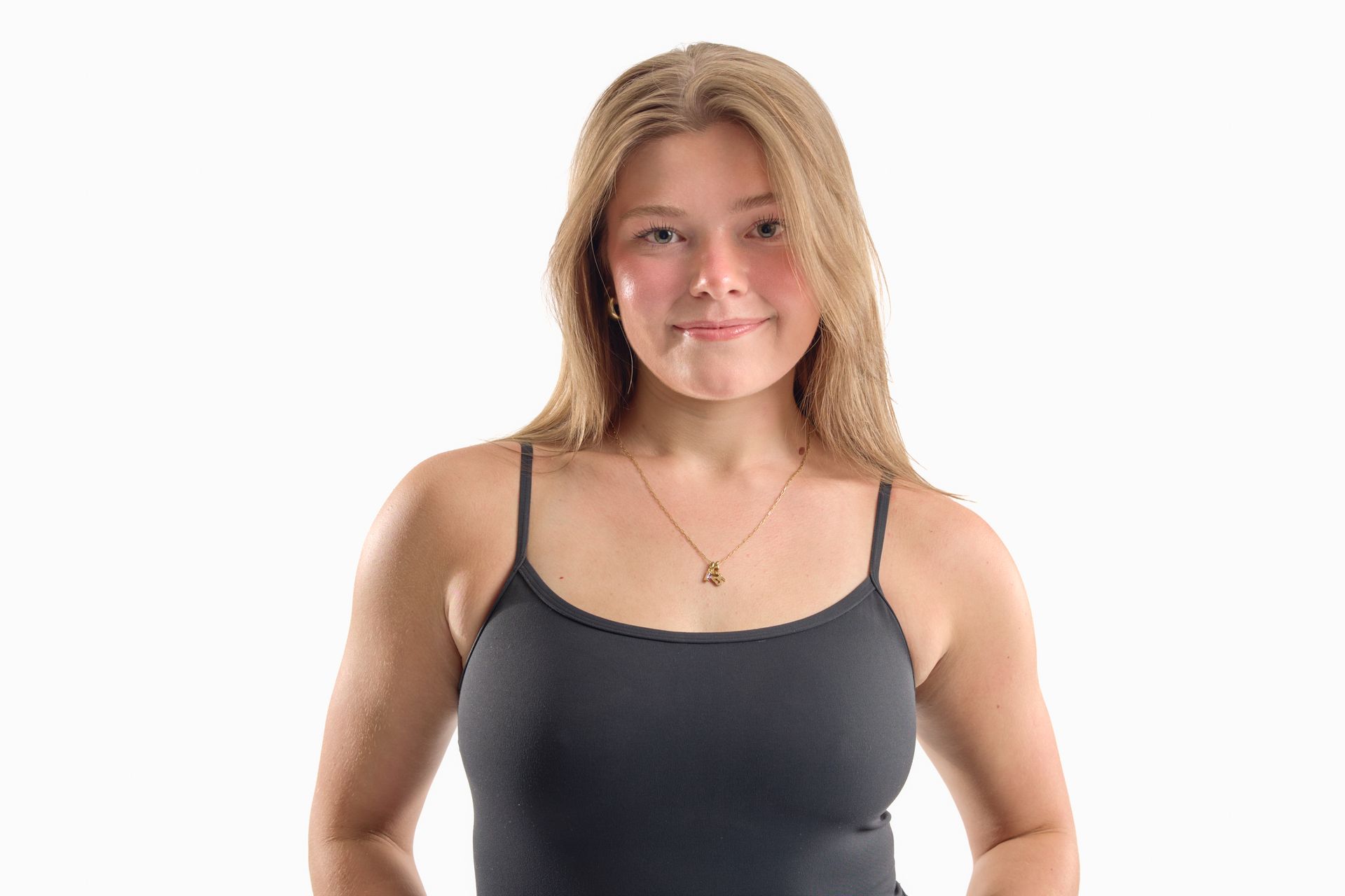Person in a black tank top standing against a white background, looking at the camera with a slight smile.