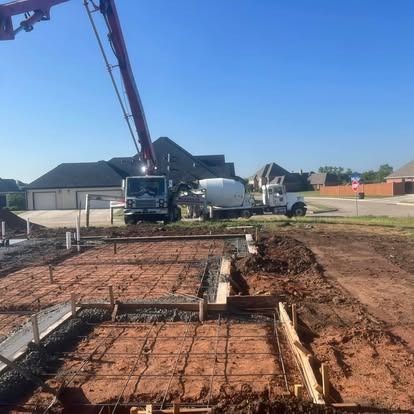 A concrete truck is pouring concrete into a foundation of a house.