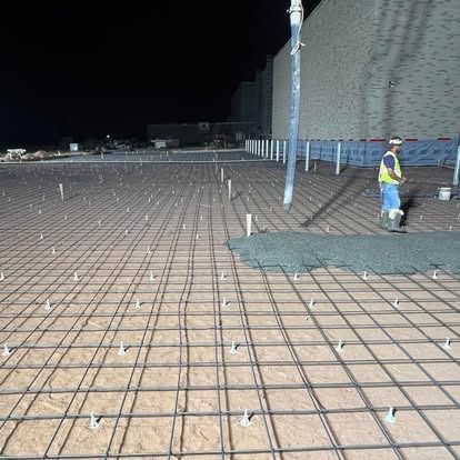 A man is standing on a concrete floor at night.
