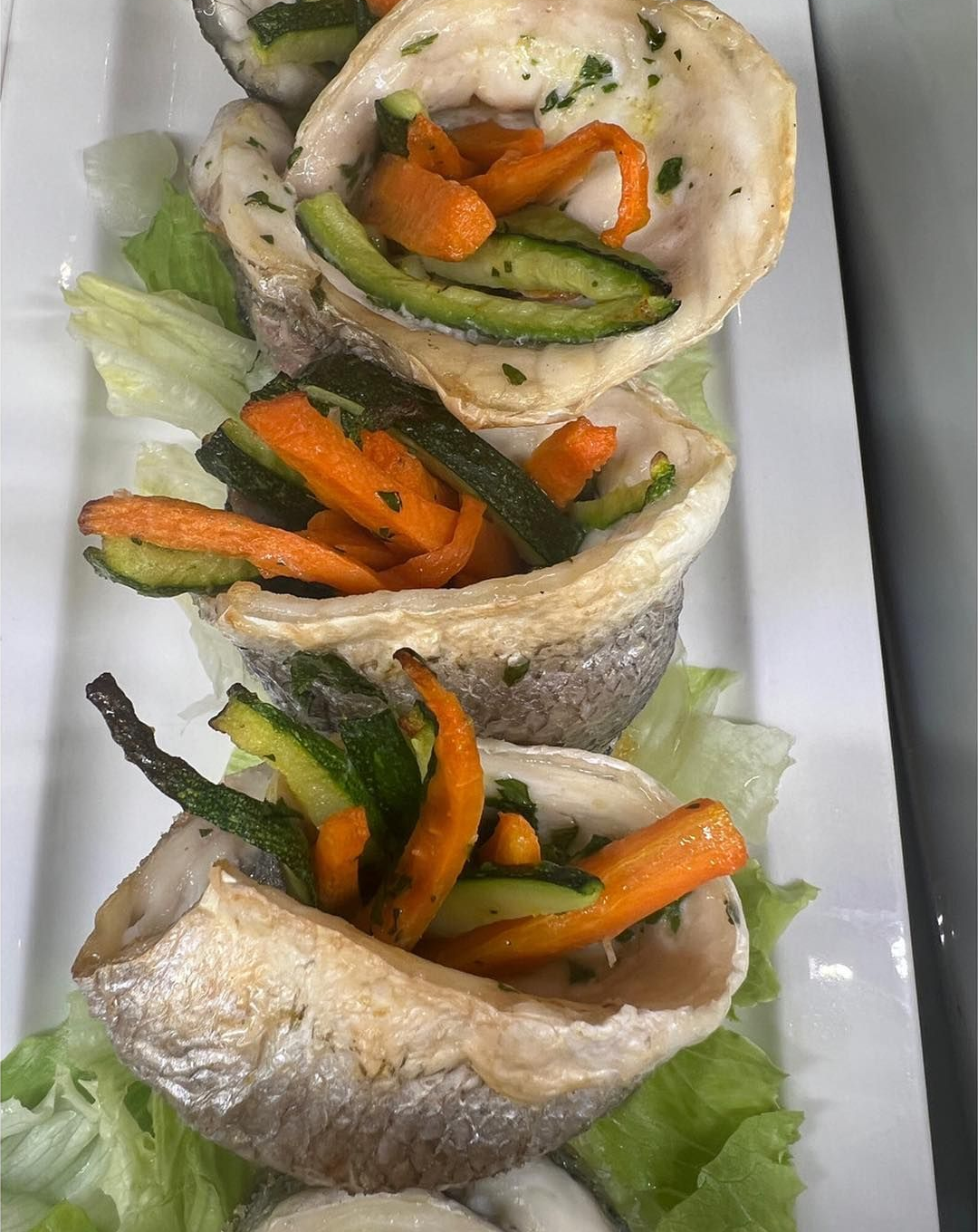 Involtini di pesce con zucchine, carote e lattuga.