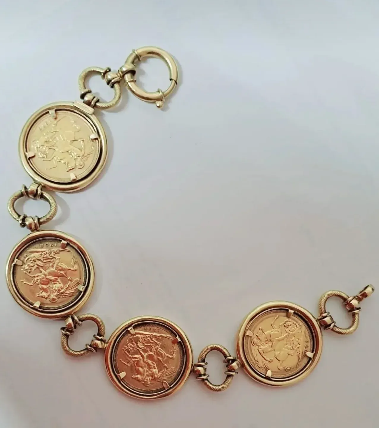 Bracciale con monete d'oro e medaglioni rotondi collegati tra loro su sfondo bianco.