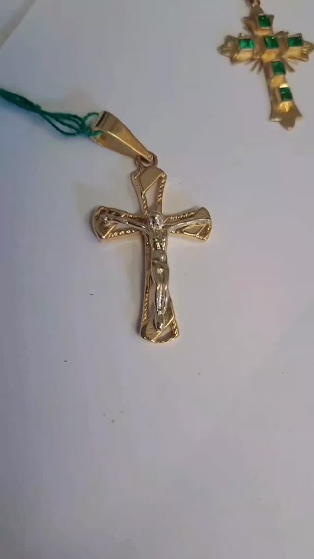 Due ciondoli a croce dorati su cordini, uno più grande e uno più piccolo, su sfondo bianco.