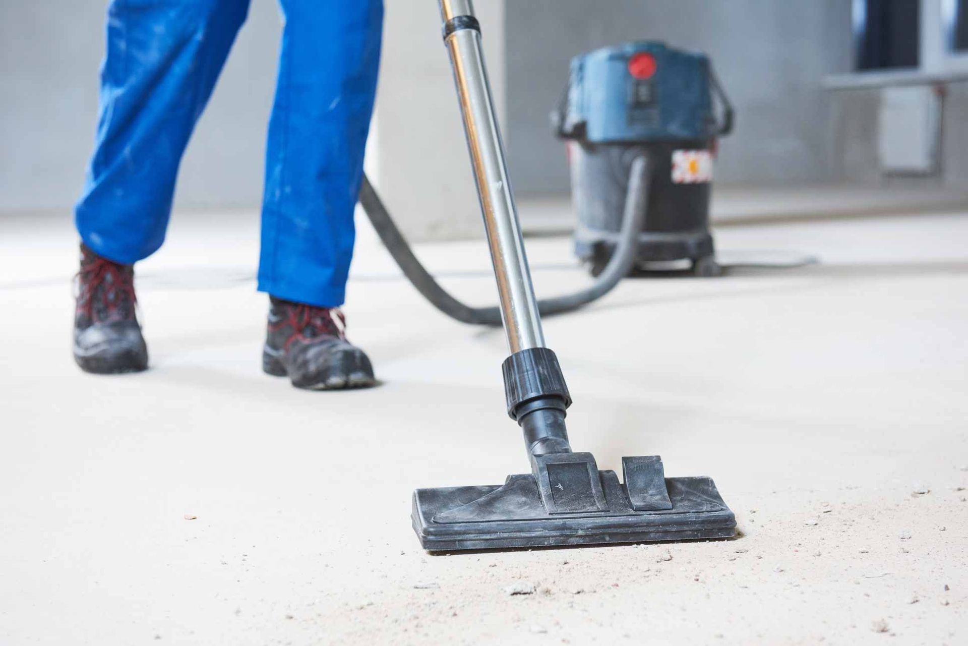 Vacuuming a dusty floor with a shop vac and floor attachment