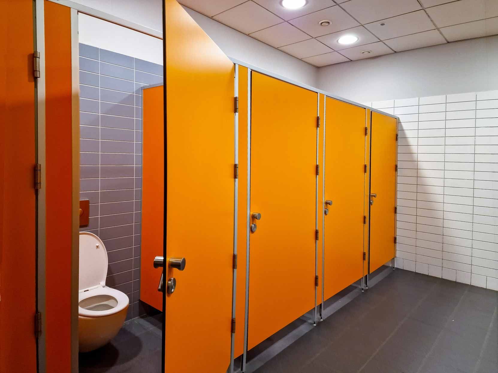 Public restroom stalls with bright orange doors and a visible toilet
