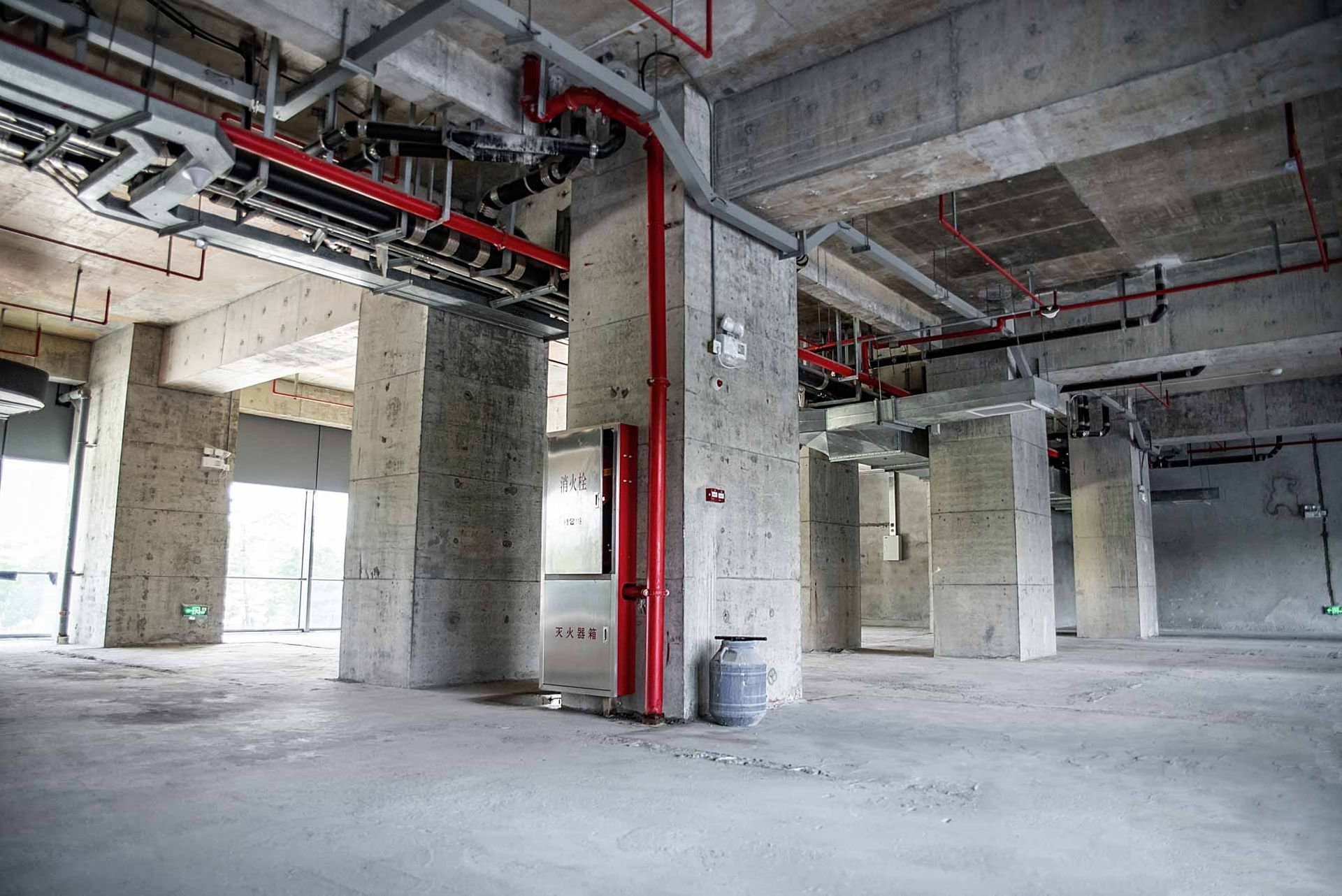 Empty concrete parking garage with exposed red pipes and columns
